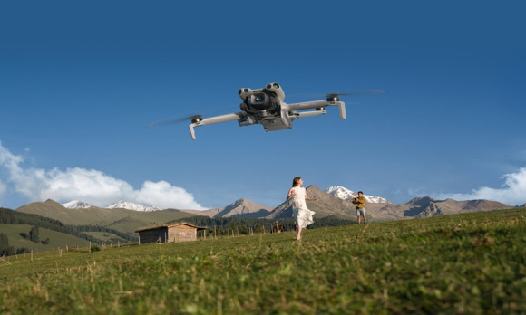 the_dji_mini_5-pro_hovers_in_a_blue_sky_over_a_green_field_in_mounains_a_woman_in_a_white_dress_runs_toward_it DJI.